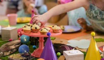 Hier sieht man einen gedeckten Geburtstagstisch mit Muffins und Dekoration.