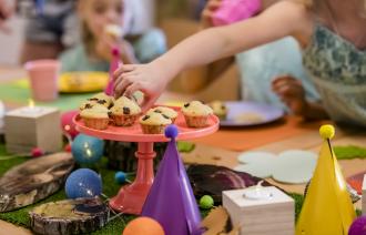 Hier sieht man einen gedeckten Geburtstagstisch mit Muffins und Dekoration.